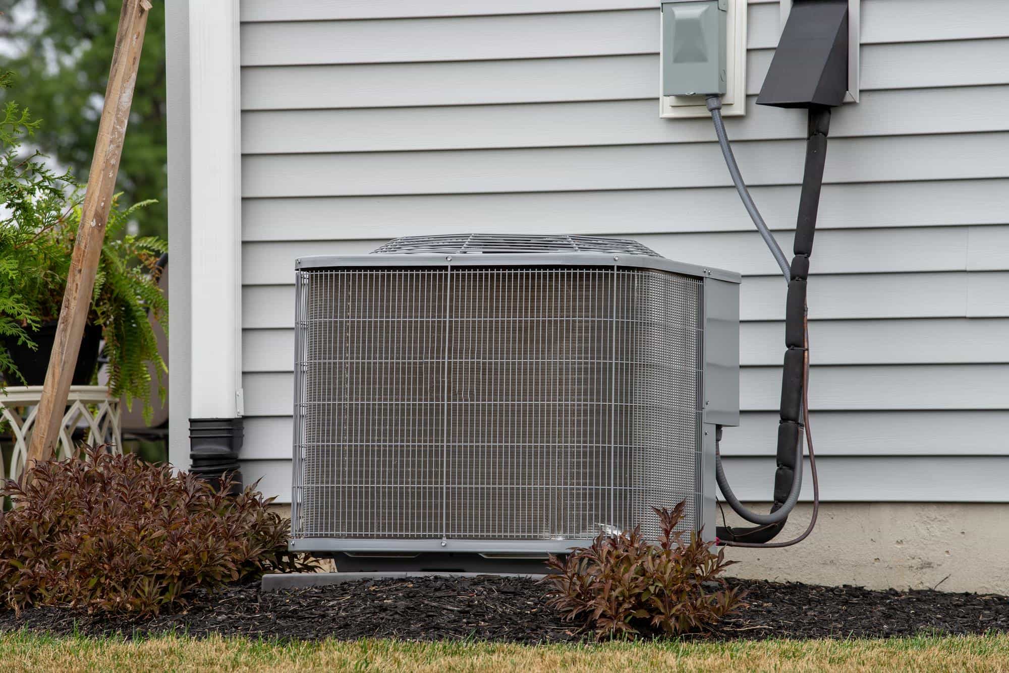 central air conditioning outdoor condenser unit installed beside house residential HVAC system
