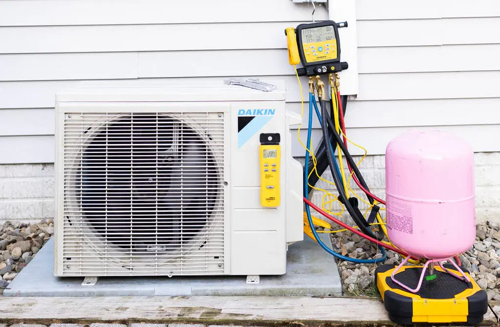 air conditioner outdoor unit with refrigerant gauges and recovery tank during HVAC service
