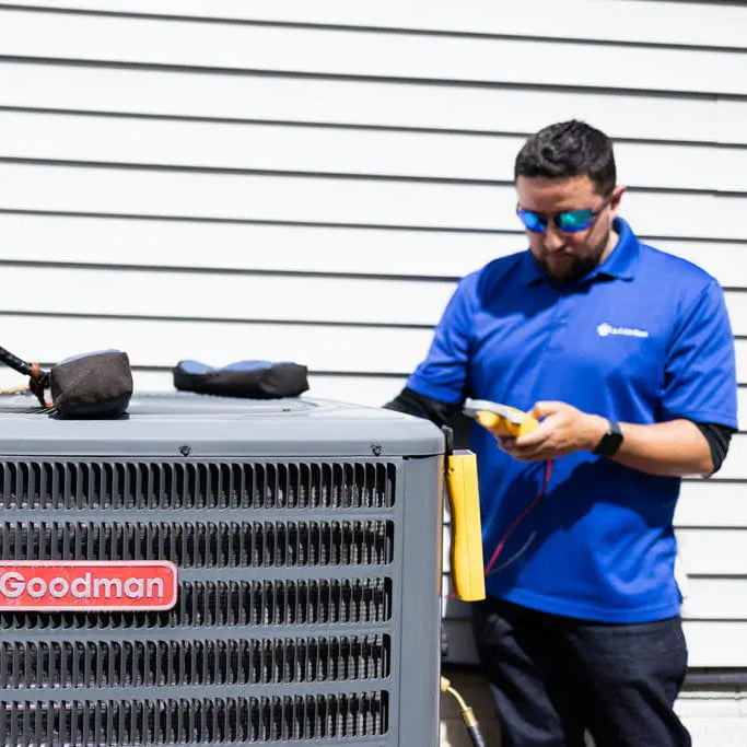 Goodman HVAC technician servicing outdoor air conditioning unit professional AC repair
