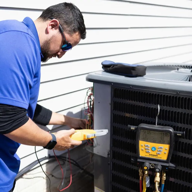 HVAC technician servicing outdoor air conditioning unit with digital manifold gauge professional AC maintenance