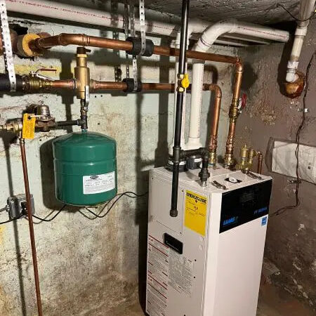 residential gas boiler system with copper piping and expansion tank in basement home heating equipment