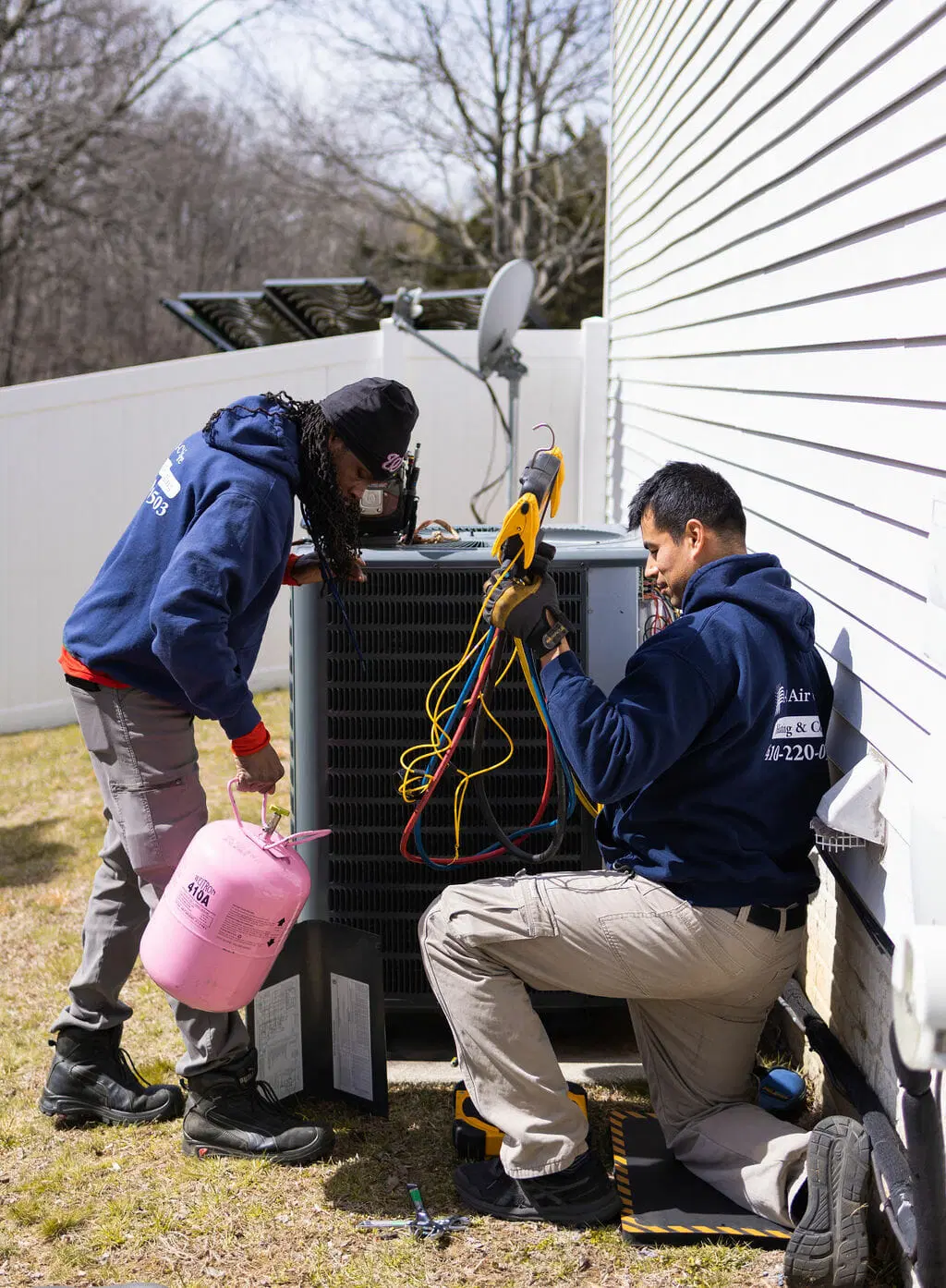 HVAC technicians performing repair and maintenance on air conditioning system with tools outdoor service